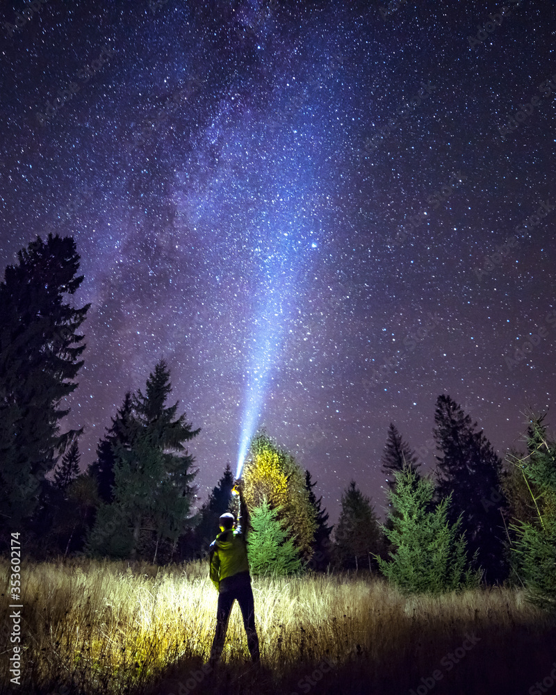 Silhouette of climber standing against the Milky Way with a flashlight in his hands. Location Carpathian, Ukraine, Europe. Astrophotography of milkyway. Dramatic scene. Discover the beauty of earth.