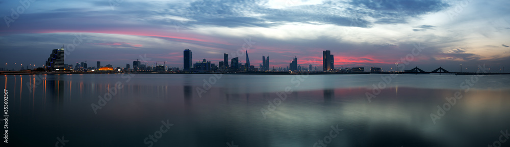 Panormic view of Bahrain skyline with dramatic clouds and reflection on water