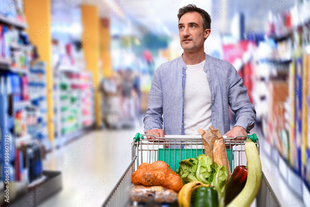 Man shopping and pushing a shopping cart in a supermarket