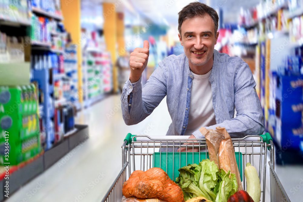 Supermarket customer making ok gesture with cart full of food