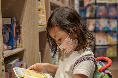 Adorable young Asian girl reading book 