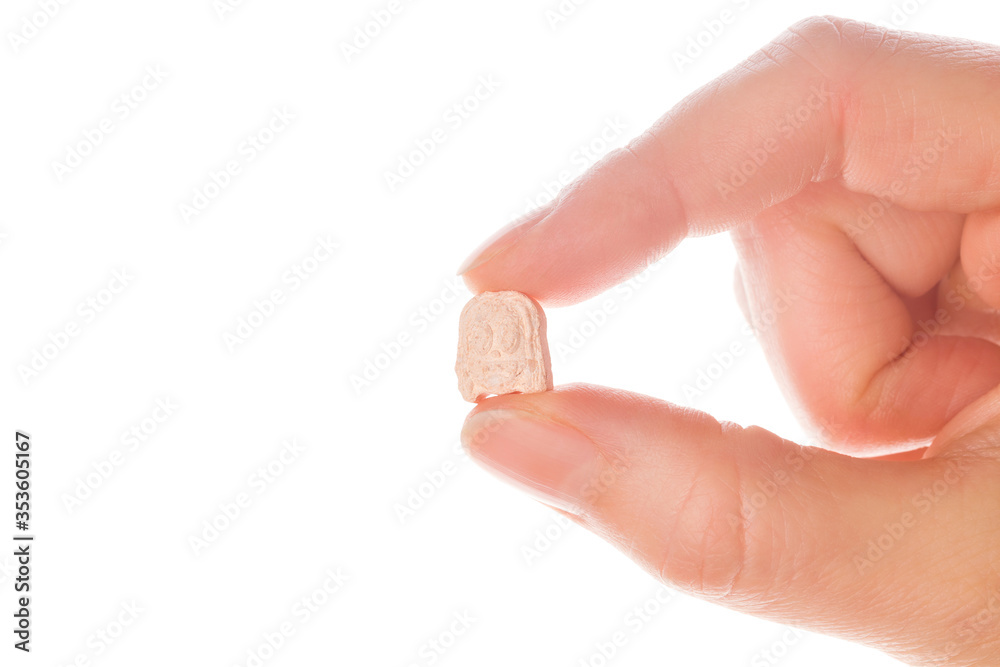 Ecstasy pill in a woman's hand isolated on white background. Ecstasy pill in a woman's hand isolated on white background.
