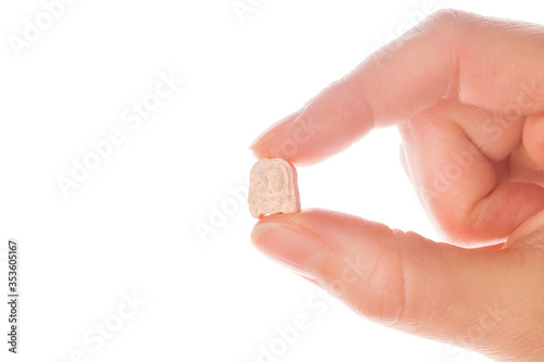 Ecstasy pill in a woman's hand isolated on white background.