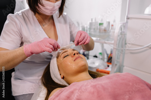 Beautician removes a clay mask from the face of a young girl in the Spa salon. Beautiful young girl at the beautician does the spa procedures