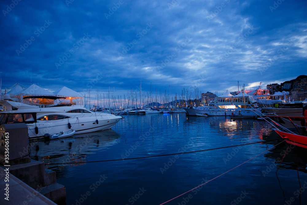 luxurious yachts and boats in the port at night. evening, pier, sea, and sky. 