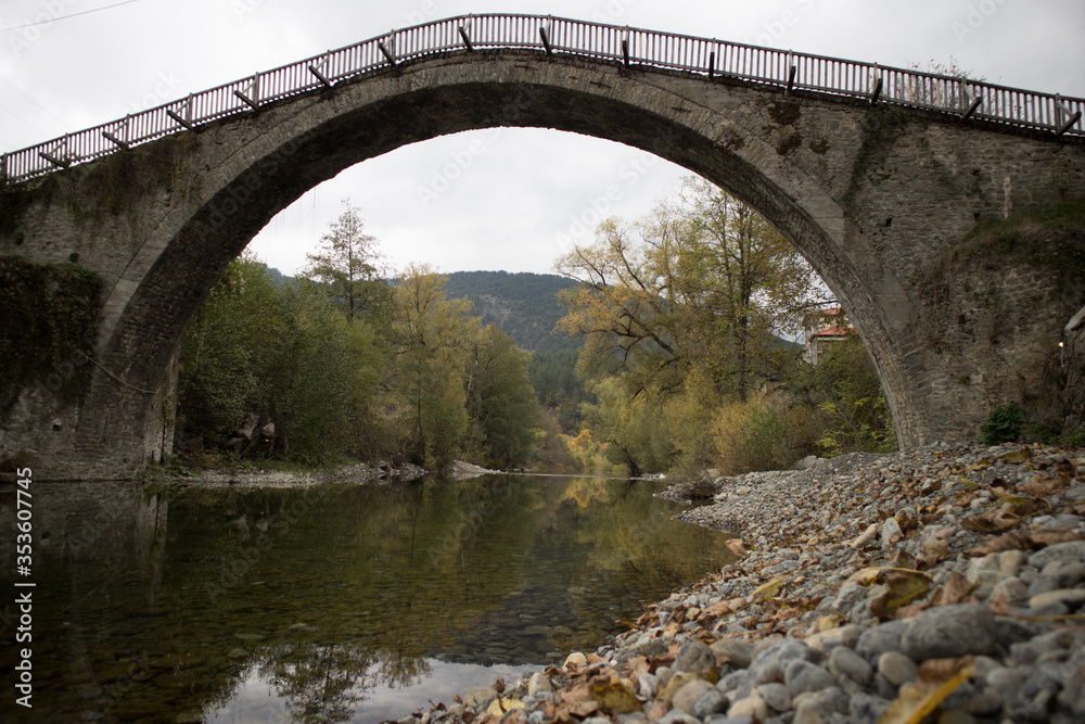 Somehow blurred view of the pedestrian stone bridge in Vovousa. It builts in 1748 above the waters river Aoos. Next to Pindus National Park (Valia Calda).
