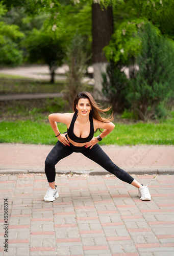 girl athlete in sports apparel, doing lunges, stretching in Park. 