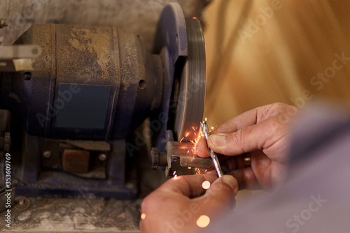 The hands of an engineering young man regrinding the drill tool for sharpen the drill tool with grinding wheel.