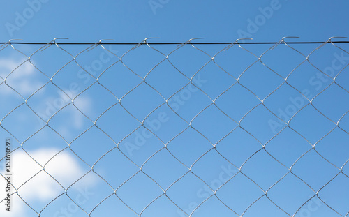 Metal mesh on the fence against the sky.