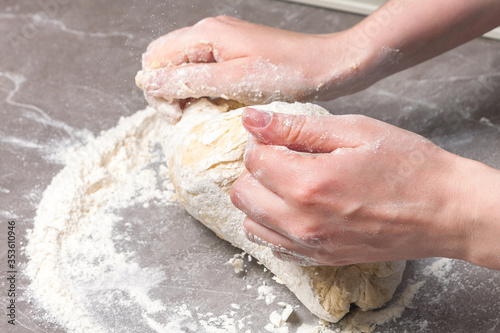 hands knead the dough on the table