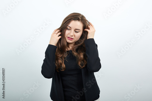 Young Attractive Woman Brunette In In A Black T-Shirt And Sweater On White Background, Gentle Female Touches Body, Stroking Her Head. The Concept Of Nice People, Kind, Sincere