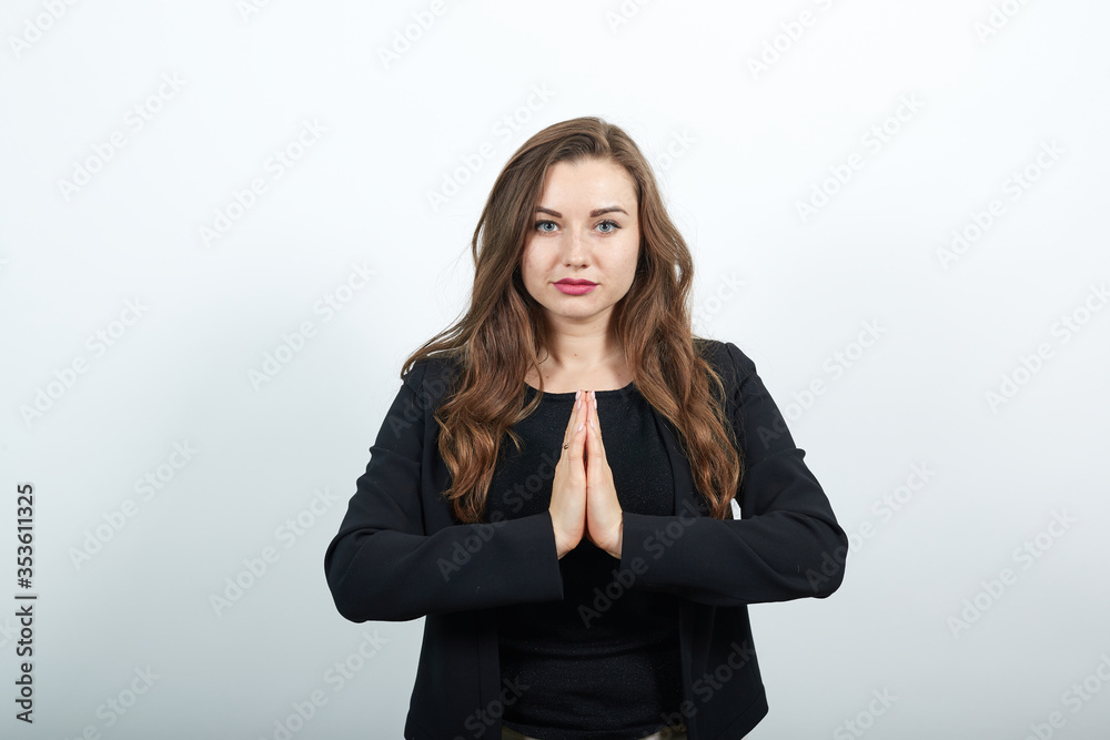 Young Attractive Woman Brunette In In A Black T-Shirt, Sweater On White Background, Religious Female Puts Her Hands Together, Prays. The Concept Of Spirituality And People's Faith In God Young Attractive Woman Brunette In In A Black T-Shirt, Sweater On White Background, Religious Female Puts Her Hands Together, Prays. The Concept Of Spirituality And People's Faith In God