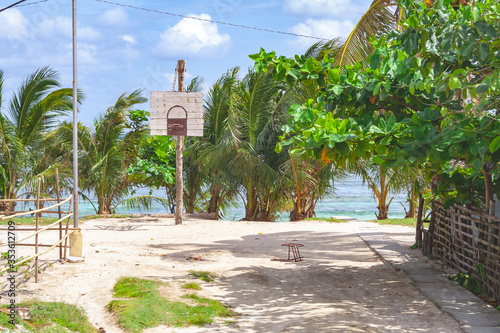 Beautiful beach with a basketball court in the Philippines with blue cloudy sky and palm trees