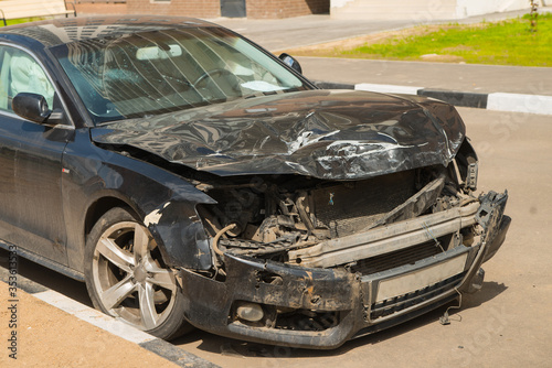 Damaged glass, hood, light and bumper of the black auto. Car accident with a lot of destructions