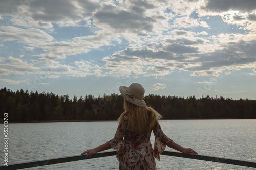 A girl in a beautiful dress on the shore of a forest lake.