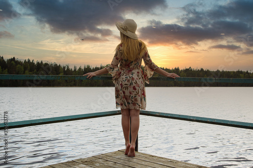 A girl in a beautiful dress on the shore of a forest lake.
