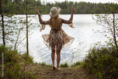 A girl in a beautiful dress on the shore of a forest lake.