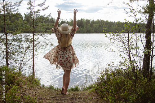 A girl in a beautiful dress on the shore of a forest lake.