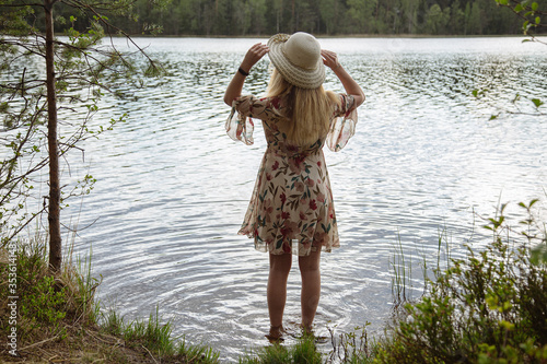 A girl in a beautiful dress on the shore of a forest lake.