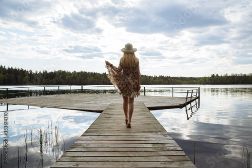 A girl in a beautiful dress on the shore of a forest lake.