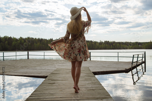 A girl in a beautiful dress on the shore of a forest lake.