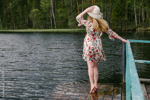 A girl in a beautiful dress on the shore of a forest lake.