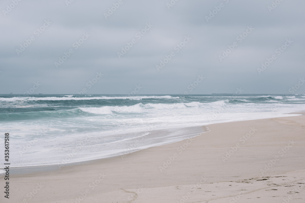 Beautiful empty moody shore of Atlantic ocean with turquoise waves and white sand