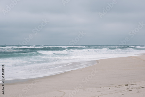 Beautiful empty moody shore of Atlantic ocean with turquoise waves and white sand