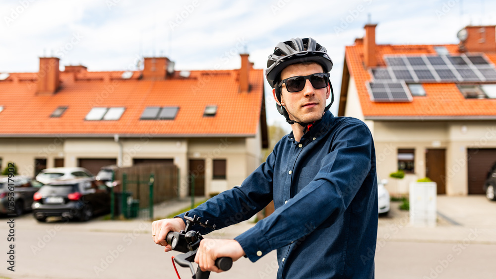 Young man riding on an electric scooter, housing estate