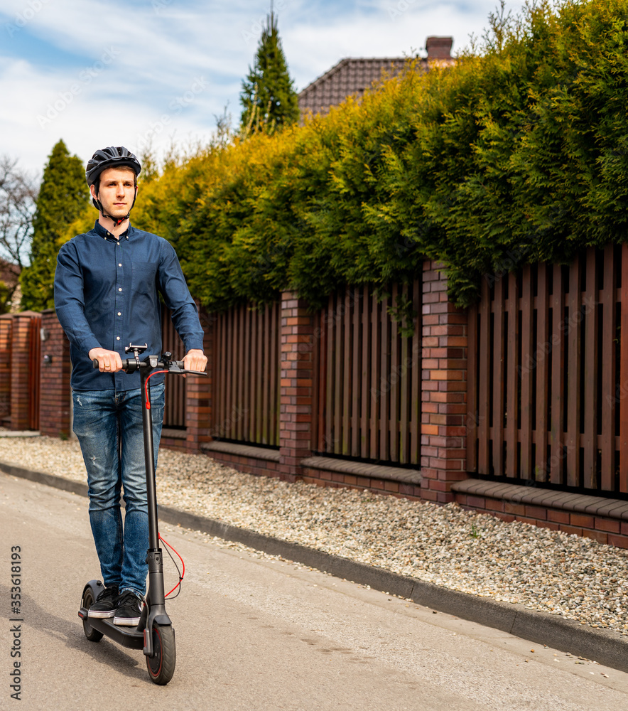 Young man riding on an electric scooter, housing estate