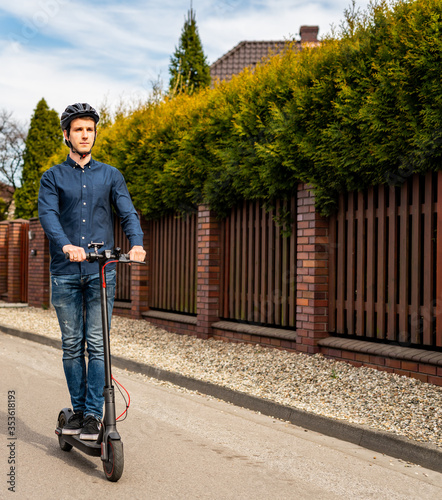 Obraz na płótnie Young man riding on an electric scooter, housing estate w salonie