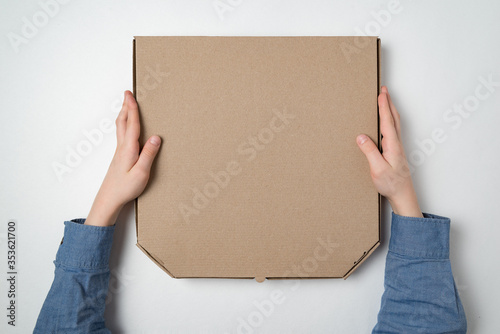Pizza box in children's hands on white background. Top view. Copy space. © somemeans