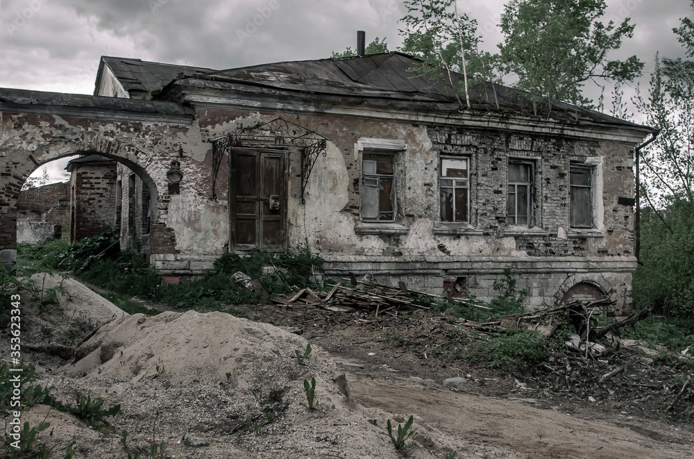 An old abandoned house with an arch stands on the street