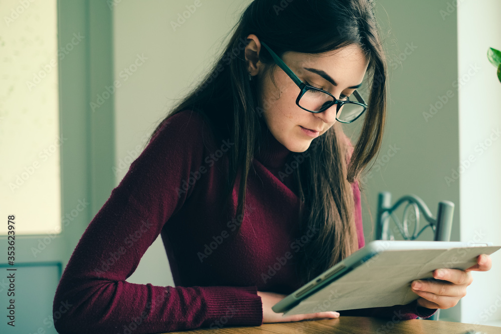 Close up of girl working on tablet from home during period of restrictions. Close up of girl working on tablet from home during period of restrictions.