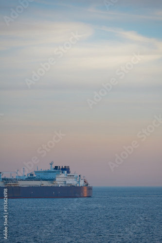 Commercial cargo ship sailing across North Sea in fading dusk light