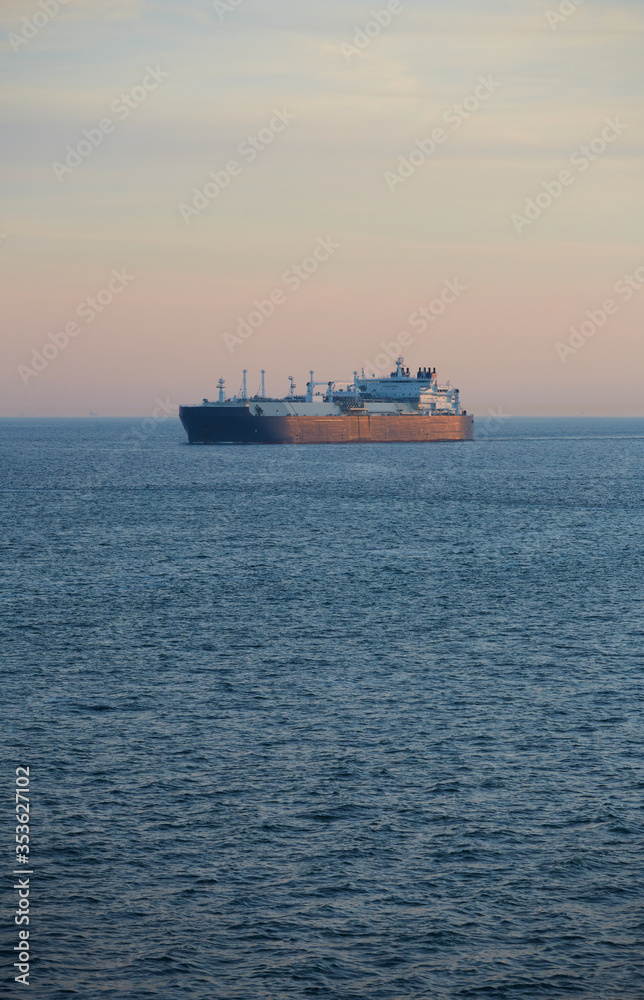 Commercial cargo ship sailing across North Sea in fading dusk light Commercial cargo ship sailing across North Sea in fading dusk light