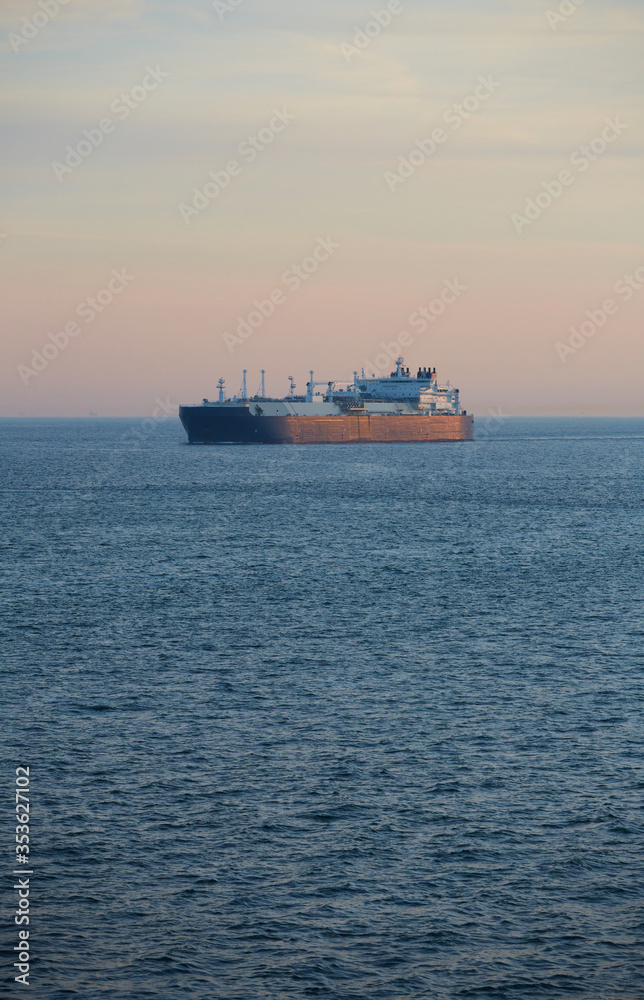 Commercial cargo ship sailing across North Sea in fading dusk light