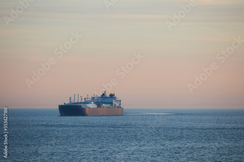 Commercial cargo ship sailing alone across North Sea in fading dusk light