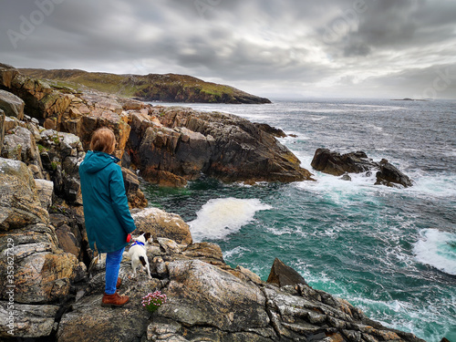 Obraz na plátně A woman and her dog stand on rugged cliffs at Hushinish on the Isle of Harris