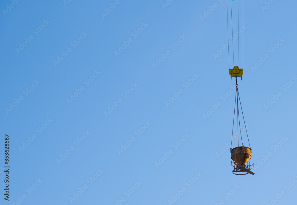 Tower crane lifting concrete bucket for pouring concrete during construction residential building on blue sky background. Builder workers during formwork and pouring concrete. New skyscraper Tower crane lifting concrete bucket for pouring concrete during construction residential building on blue sky background. Builder workers during formwork and pouring concrete. New skyscraper