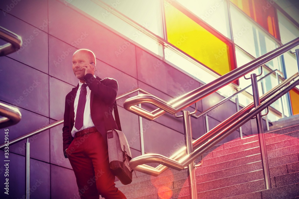 Portrait of mature businessman talking on smartphone while standing on stairs
