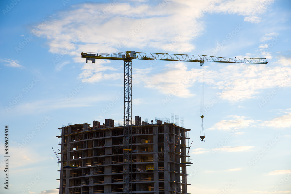 Preparing to pour a bucket of concrete into formwork.Tower crane lifting cement bucket during construction a multi-storey residential building. Construction cranes and builders in action