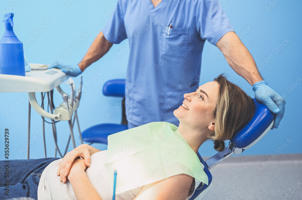 Dentist examining a patient's teeth using dental equipment in dentistry office. Stomatology and health care concept. Young handsome male doctor in disposable medical facial mask, smiling happy woman. Dentist examining a patient's teeth using dental equipment in dentistry office. Stomatology and health care concept. Young handsome male doctor in disposable medical facial mask, smiling happy woman.