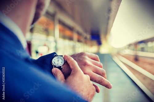 Canvastavla Rear view of businessman looking at his watch while waiting in train station