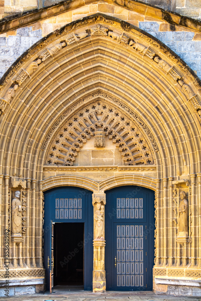 Entrance door and main facade of old stone church in Guernica, Basque Country, Spain. Romanesque architecture concept. Religion and faith concept. Facade of antique castle in Europe. Vertical shot.