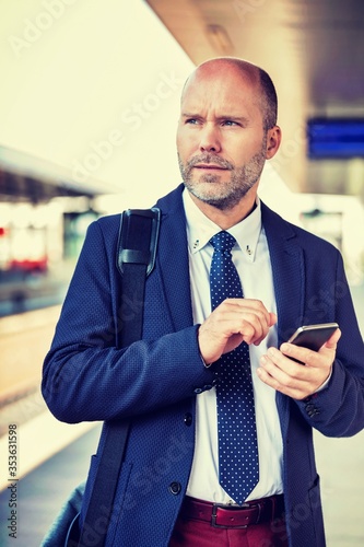 Portrait of businessman using smartphone while waiting for the train in station
 photo