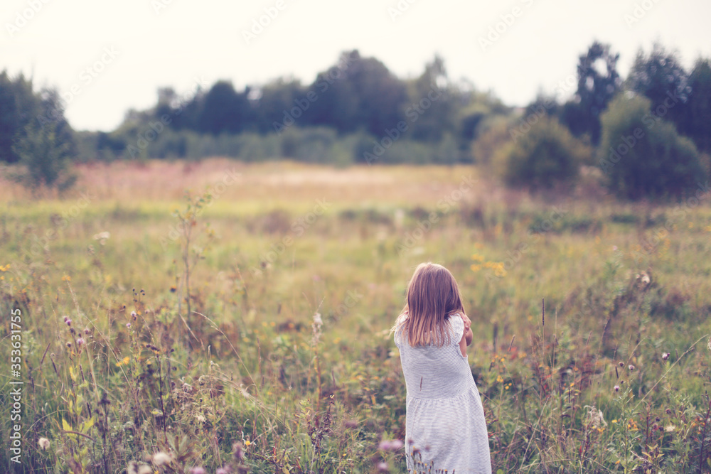 Caucasian child girl in the field, view from the back. Mood concept