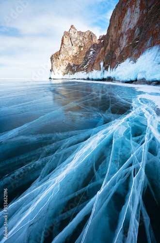 Siberian Baikal Lake in the winter. Beautiful landscape with clear transparent ice with lines of cracks near the icy cliffs of Olkhon Islands. Natural background. Close-up view
