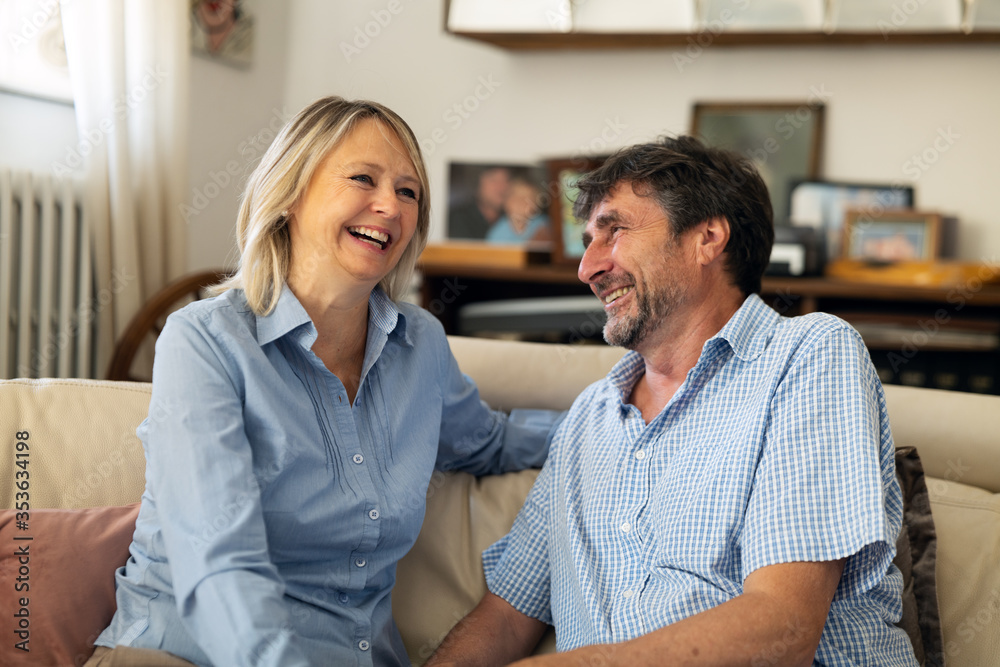 A lovely happy mature couple enjoying time together and smiling on sofa in living room at home. A lovely happy mature couple enjoying time together and smiling on sofa in living room at home.