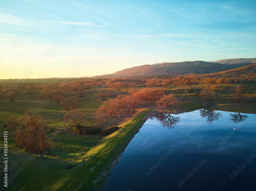 Aerial view of beautiful rural landscape at sunset with a lake and green meadows in autumn